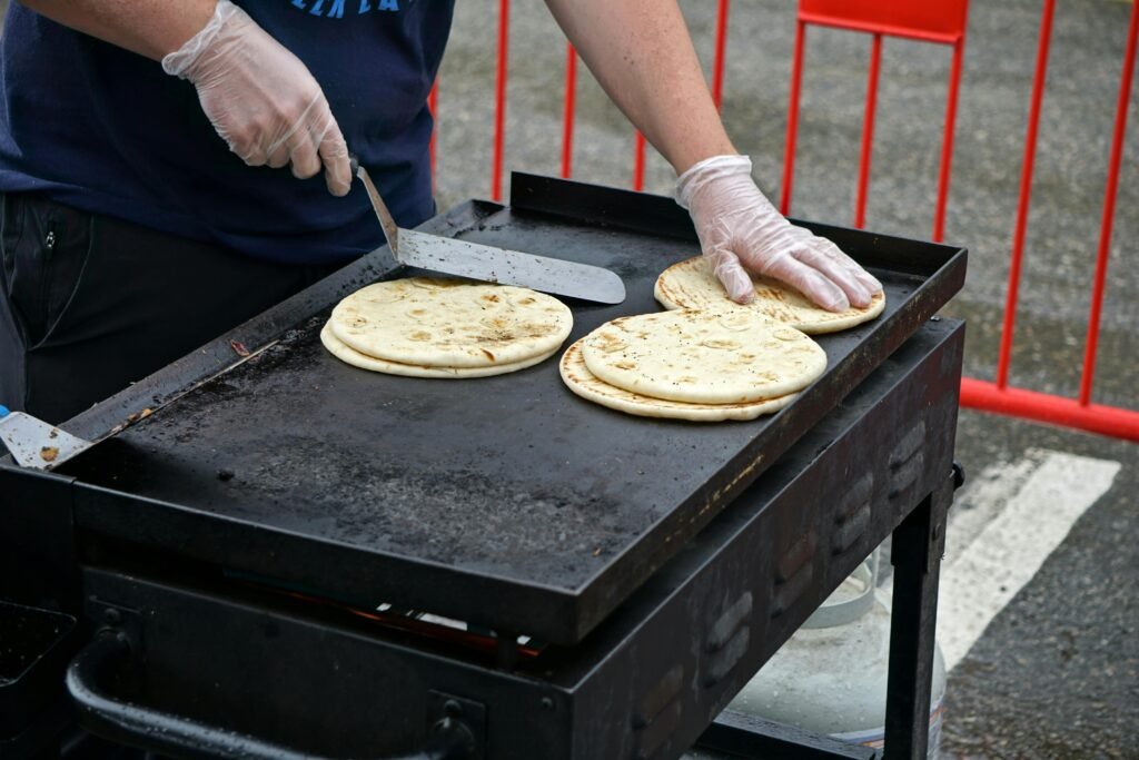 Vendor grilling pita bread at an outdoor food stand, showcasing street food preparation.