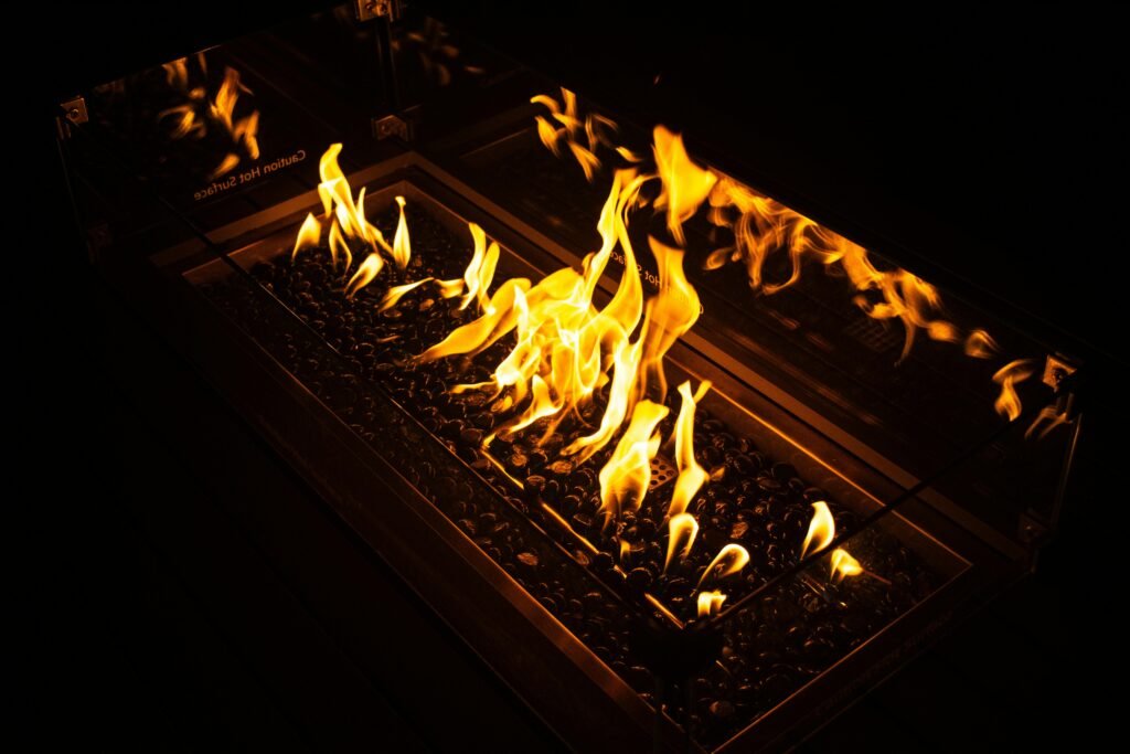 A captivating fire pit with dancing flames and glowing coals against a dark backdrop. Ideal for cozy atmospheres.